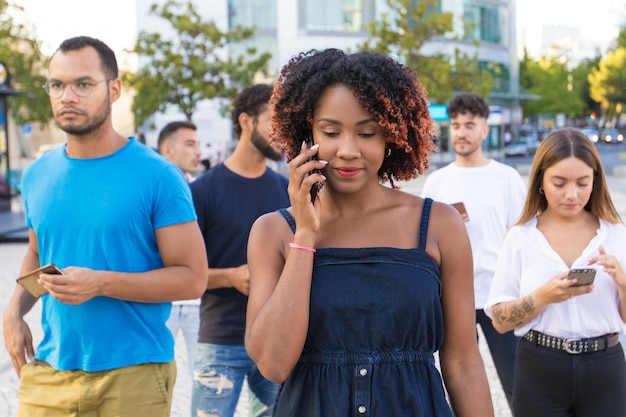 Unterschiedliche Gruppe von Personen, die ihre Smartphones beim Gehen verwendet