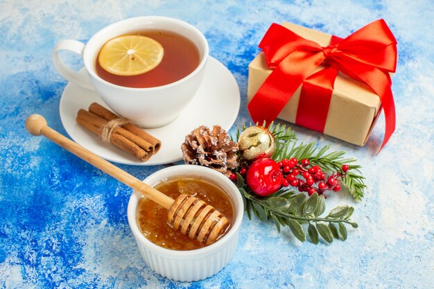 Untersicht Tasse Tee Honig und Honig Stick in Schüssel auf blauem Tisch