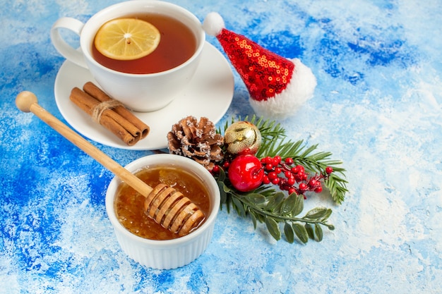 Untersicht Tasse Tee Honig und Honig Stick in Schüssel Weihnachtsmütze auf blauem Tisch