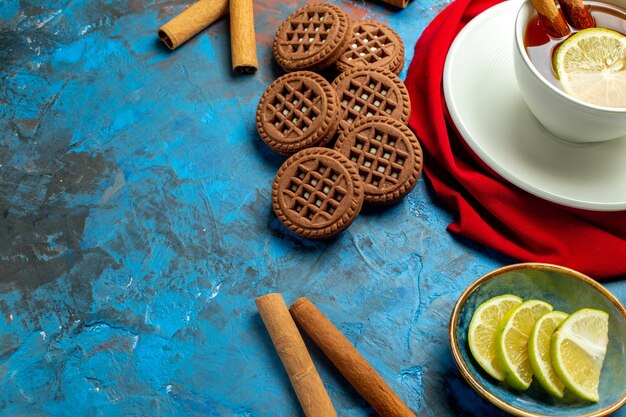 Untersicht Tasse Tee mit zitronen- und zimtrotem Schal auf blauroter Oberfläche mit freiem Platz