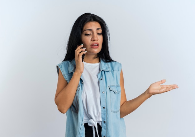 Unzufriedene junge kaukasische Frau spricht am Telefon und schaut nach unten