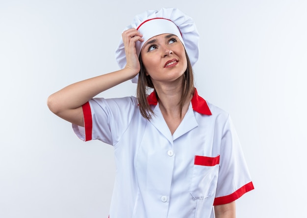 Unzufriedene junge Köchin in Kochuniform, die Hand auf den Kopf legt, isoliert auf weißem Hintergrund