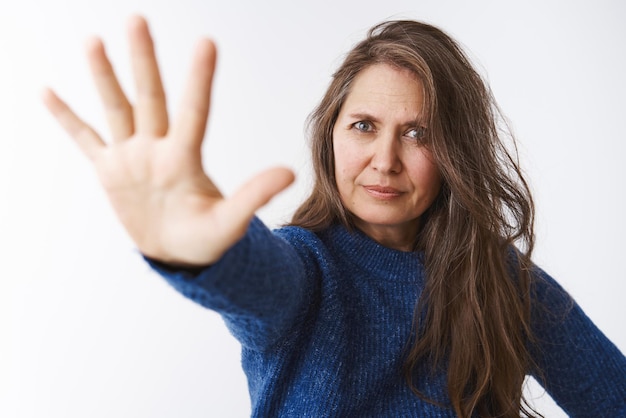 Unzufriedene strenge und herrische Frau, die in einer verbotenen Geste die Handfläche zur Kamera zieht und unzufrieden und unzufrieden aussieht