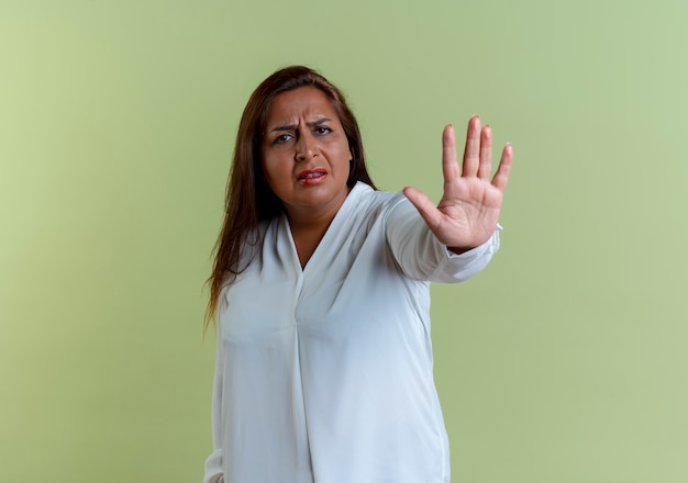 Unzufriedene zufällige kaukasische Frau mittleren Alters, die Stoppgeste zeigt, die auf olivgrüner Wand lokalisiert wird