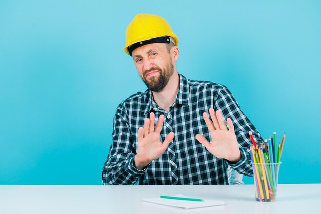 Unzufriedener Ingenieur zeigt Stoppgeste mit Händen auf blauem Hintergrund