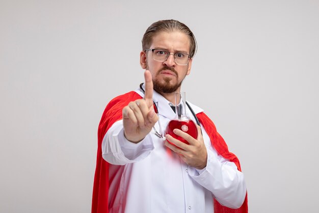 Unzufriedener junger Superheld, der medizinische Robe mit Stethoskop und Brille trägt