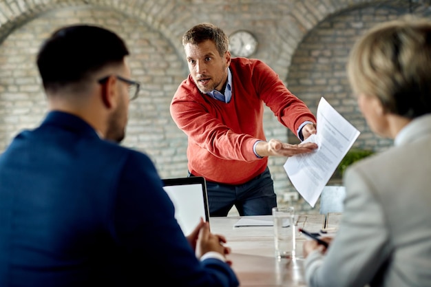 Unzufriedener Kandidat, der während des Vorstellungsgesprächs im Büro mit der Personalabteilung über seinen Lebenslauf diskutiert