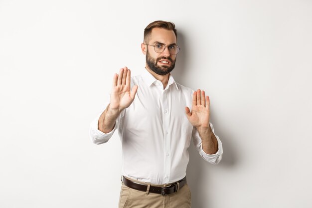 Unzufriedener Mann, der etwas Störendes ablehnt, Stoppschild zeigt und ablehnt, erschreckt vor Abneigung