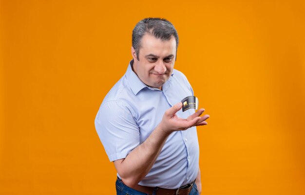 Unzufriedener Mann mittleren Alters im blau gestreiften Hemd, das Kreditkarte mit Fingern biegt