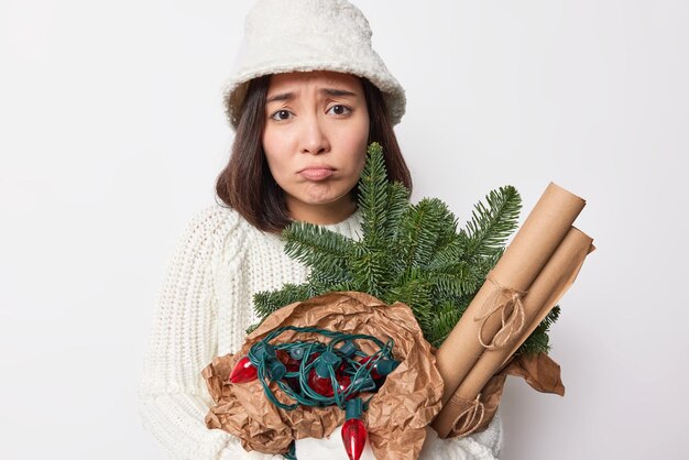 Unzufriedenheit Asiatin in Winterkleidung drückt negative Emotionen aus Posen mit Accessoires für Neujahrsdekoration isoliert auf weißem Hintergrund fühlt sich schön an und feiert Feiertage allein