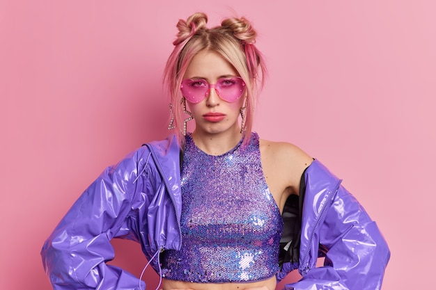 Unzufriedenheit blonde modische Frau kommt auf achtziger Jahre Disco-Party unzufrieden mit Musik schaut traurig in die Kamera trägt trendige rosa Schattierungen stilvolle lila Kleidung