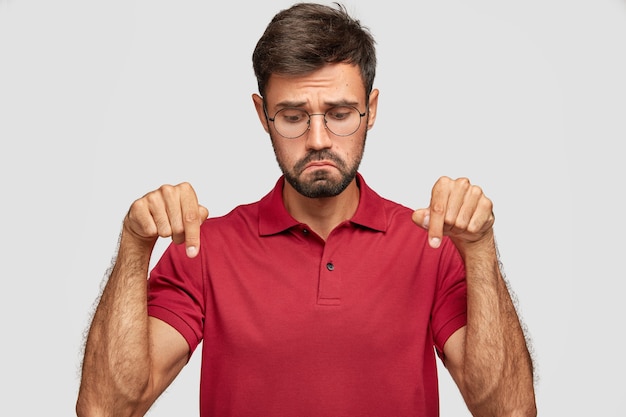 Kostenloses Foto unzufriedenheit junger emotionaler mann, der gegen die weiße wand aufwirft