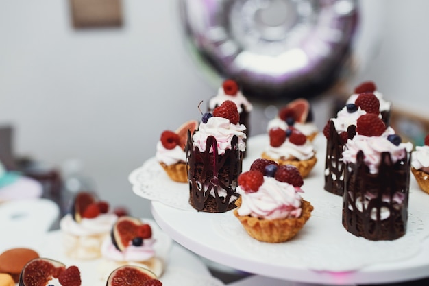 Ursprüngliche Süßigkeiten mit Beeren und Schokoladen serviert auf weißem Plat