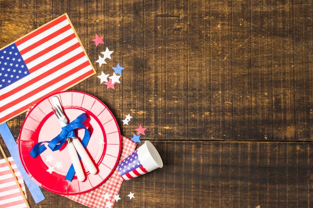 Usa Flagge Teller und Besteck mit blauem Band mit Flagge gebunden; Stern und Wegwerfschale auf hölzernem Schreibtisch