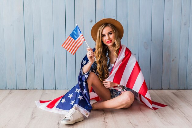 USA-Unabhängigkeitstagkonzept mit der sitzenden Frau, die Flagge hält