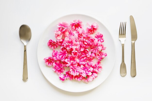 Utensilien in der Nähe von Blumen auf dem Teller