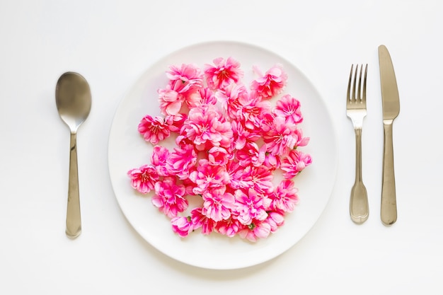 Utensilien in der Nähe von Blumen auf dem Teller