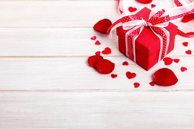 Valentine Geschenk-Box und Rosenblätter auf dem weißen Holzbrett