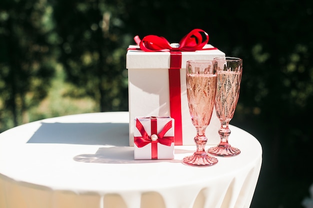 Valentinsgrüße oder Hochzeitstagkonzept mit Paaren von Champagnergläsern und von Geschenkboxen