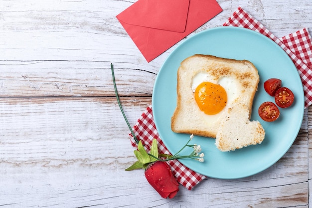 Kostenloses Foto valentinstag-frühstück mit ei mit herzförmigen tomaten und toastbrot auf holztisch x a
