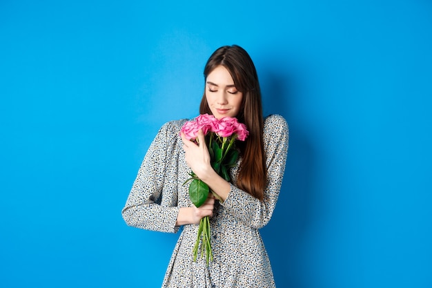 Valentinstag Konzept leidenschaftliche und romantische junge Frau umarmt Bouquet von Geschenkrosen, die nach Fl...