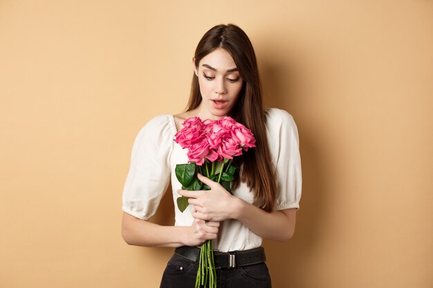 Valentinstag überrascht zartes Mädchen, das schöne rosa Rosen betrachtet, ein romantisches Geschenk von der Liebe erhalten ...