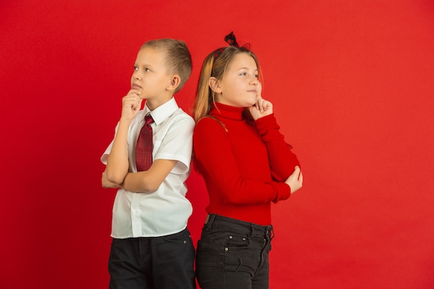 Valentinstagfeier, glückliche, niedliche kaukasische Kinder lokalisiert auf rotem Studio