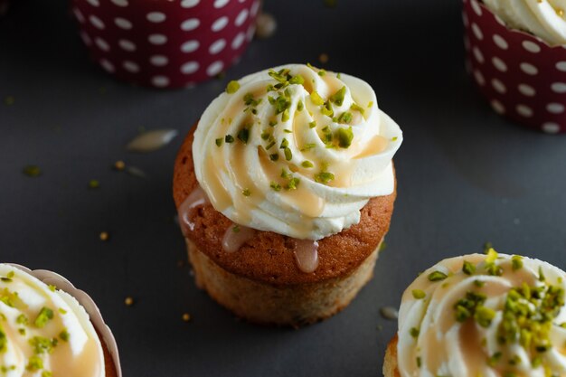 Vanille-Cupcakes mit Sahne und Karamell auf grauem Tischhintergrund.