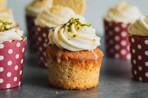 Vanille-Cupcakes mit Sahne und Karamell auf grauem Tischhintergrund.