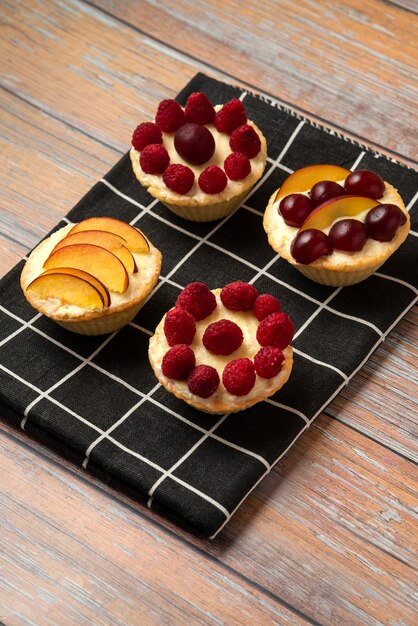 Vanille-Cupcakes mit Sommerbeerenfrüchten auf dem schwarzen Handtuch