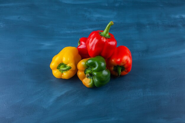 Variation verschiedenfarbiger Paprika auf blauer Oberfläche.