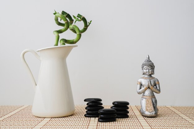 Vase mit Bambus, schwarzen Steinen und Buddha-Figur