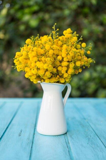 Vase mit gelben Blumen auf dem blauen Oberfläche