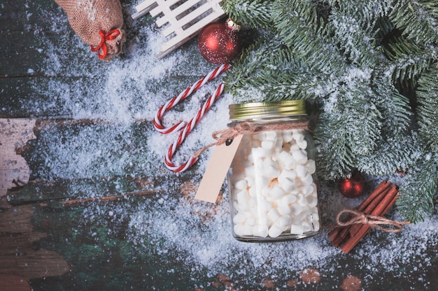 Kostenloses Foto vase mit marshmallows auf schnee und weihnachtsdekorationen