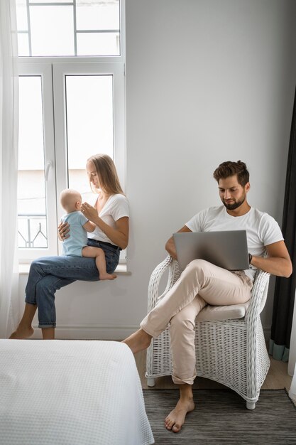 Vater arbeitet von zu Hause aus während der Quarantäne, während Mutter das Kind hält