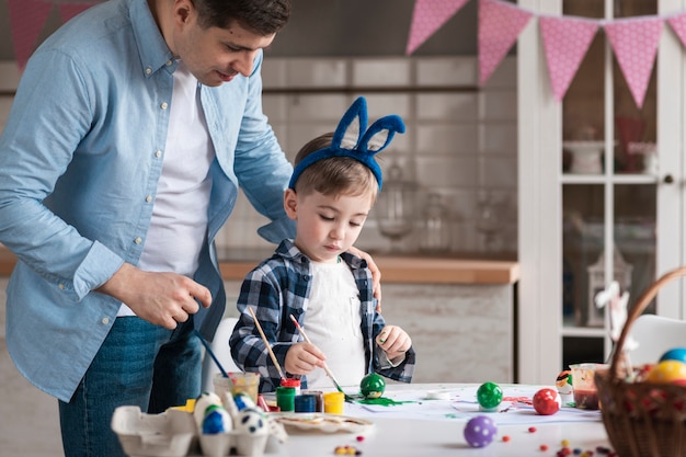 Kostenloses Foto vater bringt dem kleinen jungen bei, wie man eier für ostern malt