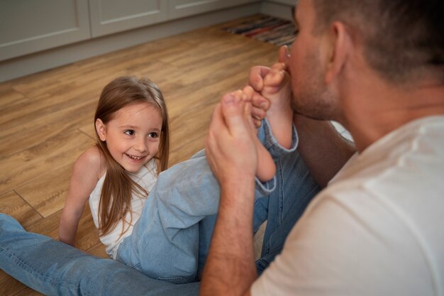 Vater bringt seine Tochter zum Lachen, indem er sie kitzelt