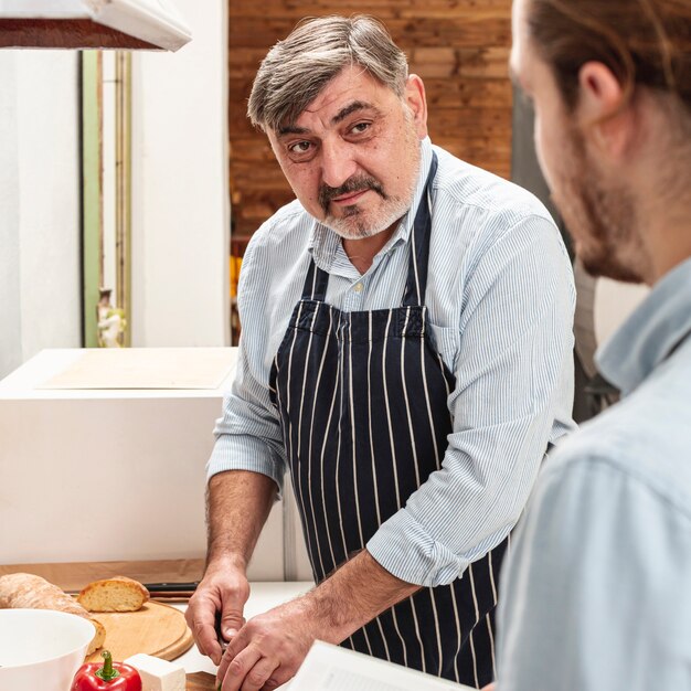 Vater, der Abendessen vorbereitet und seinen Sohn betrachtet