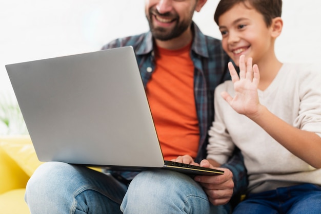 Vater, der eine Laptop- und Kleinkindbegrüßung hält