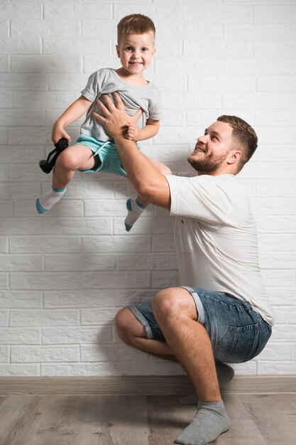 Vater, der in der Hand Sohn mit Steuerknüppel anhebt