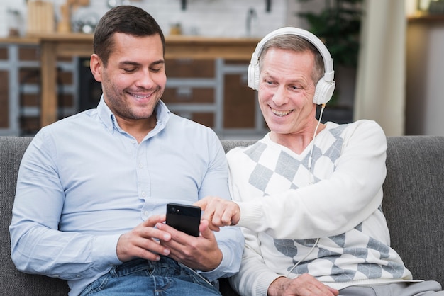 Kostenloses Foto vater, der musik vom telefon seines sohns wählt