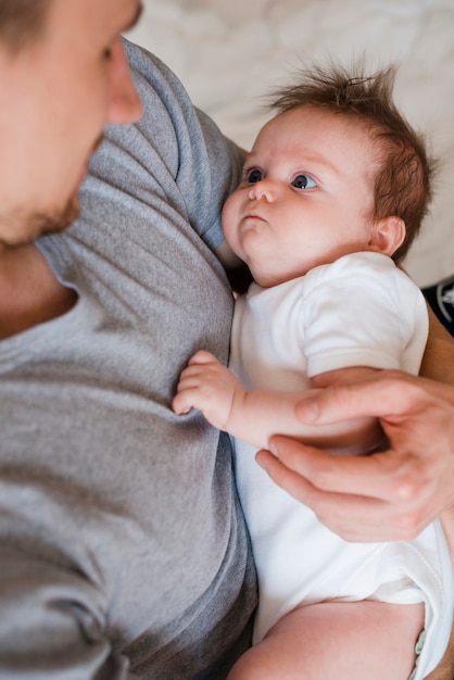 Vater, der nettes Baby auf Bett hält