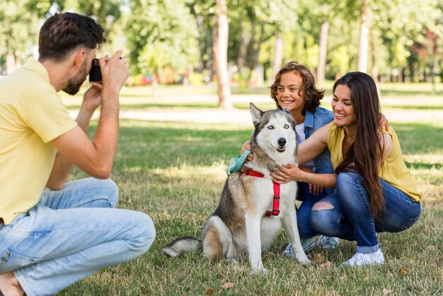 Vater fotografiert Mutter und Sohn mit Hund im Park