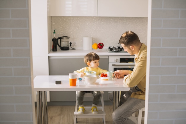 Vater füttert seinen Sohn am Tisch