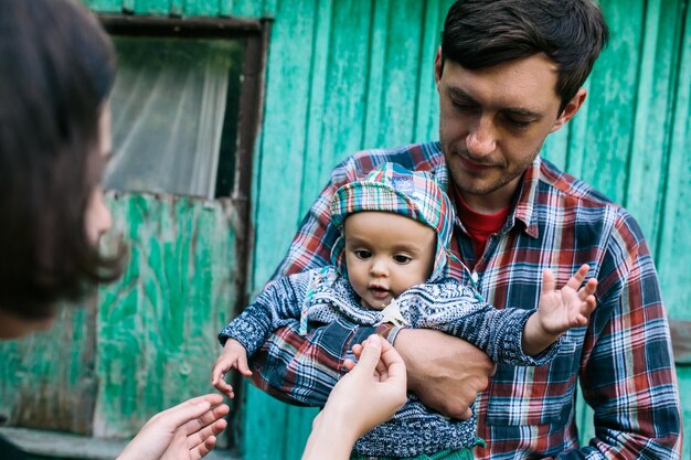 Vater hält Baby stehend außerhalb des Hauses