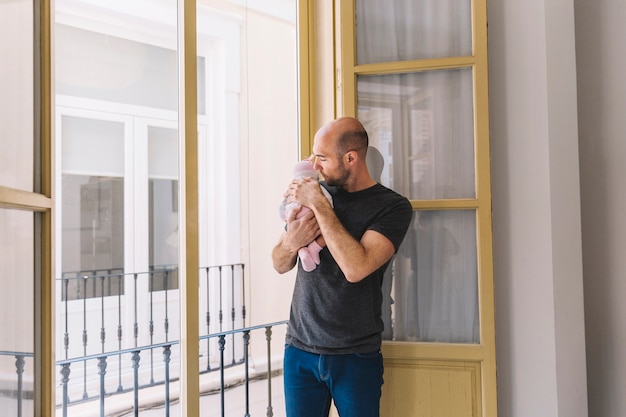 Vater hält Baby vor dem Fenster