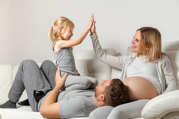 Vater hält kleines Mädchen, während Mutter mit ihr spielt