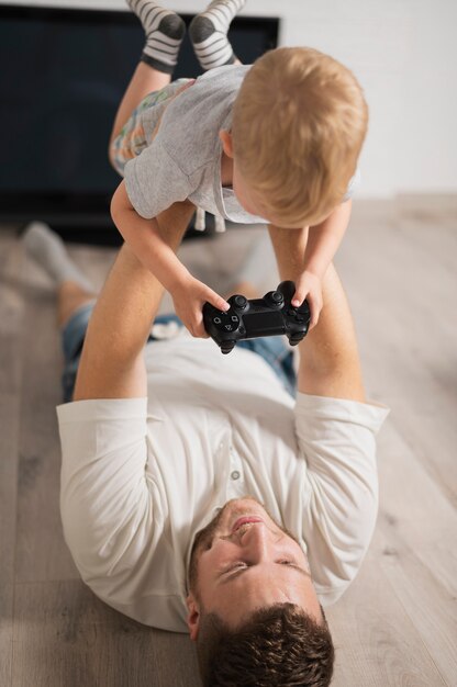 Vater hält Sohn mit Joystick in der Luft