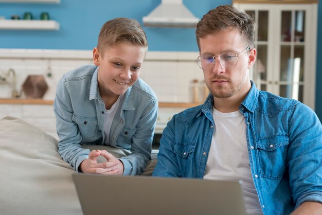 Vater mit Brille und Kind schaut auf den Laptop