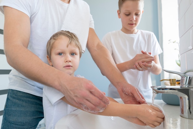 Vater mit Geschwistern beim Händewaschen Seitenansicht